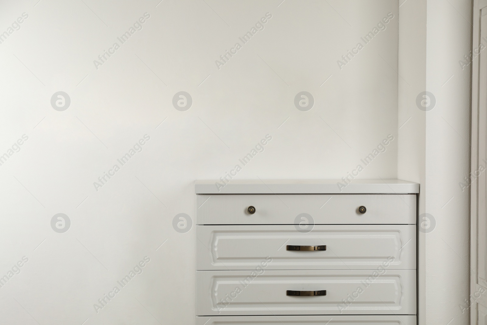 Photo of Modern chest of drawers near white wall