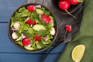 Tasty salad with radish in bowl on blue wooden table, flat lay