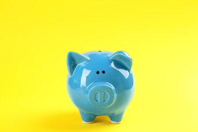 Photo of Cute blue piggy bank on yellow background