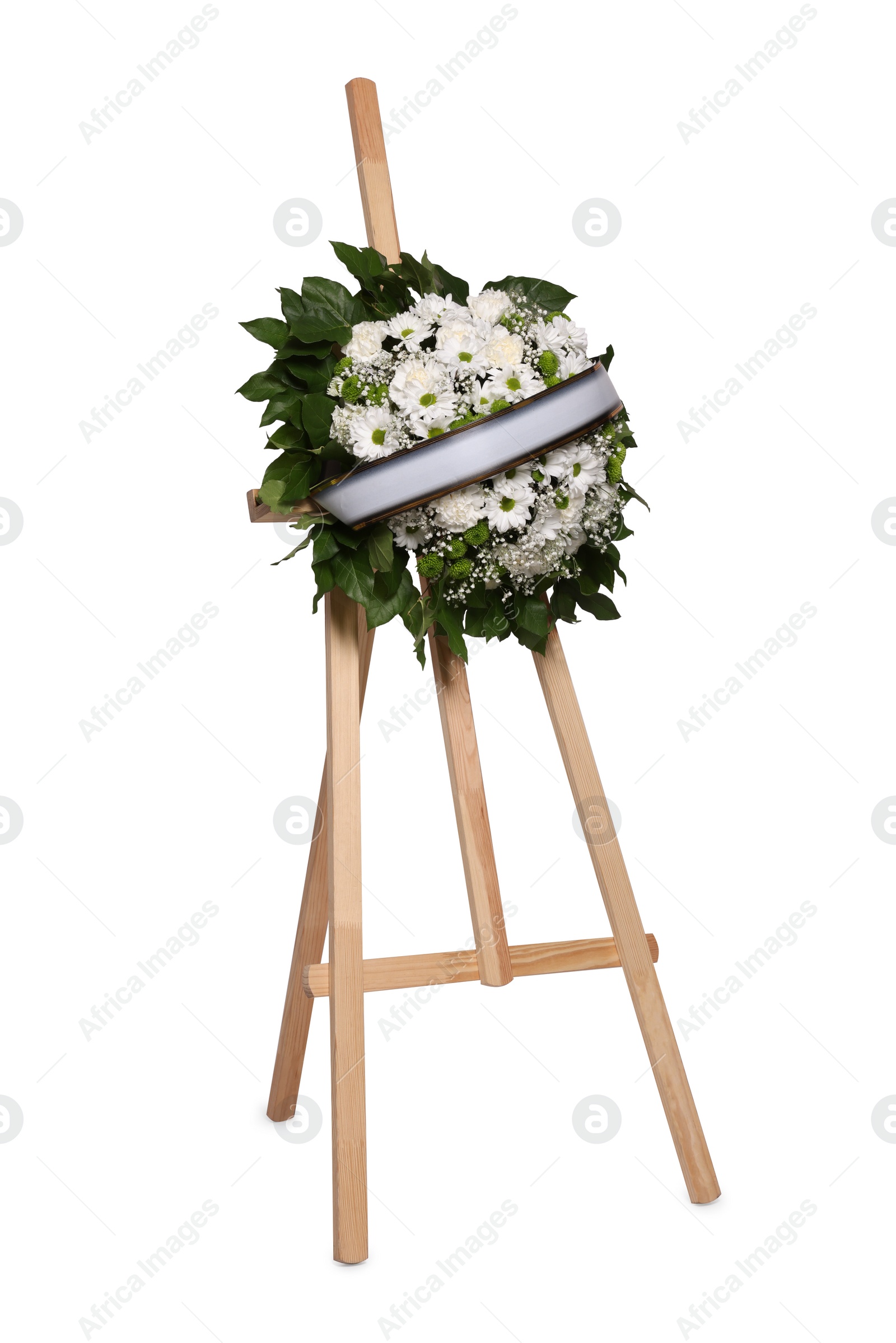 Photo of Funeral wreath of flowers with ribbon on wooden stand against white background