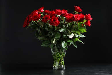 Vase with beautiful red rose flowers on black background