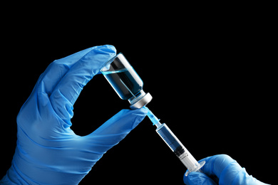 Photo of Doctor filling syringe with medication on black background, closeup. Vaccination and immunization