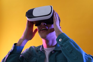 Young man with virtual reality headset on yellow background