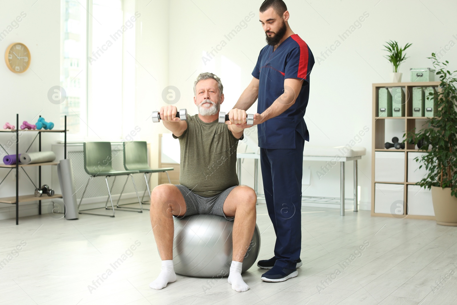 Photo of Physiotherapist working with patient in clinic. Rehabilitation therapy