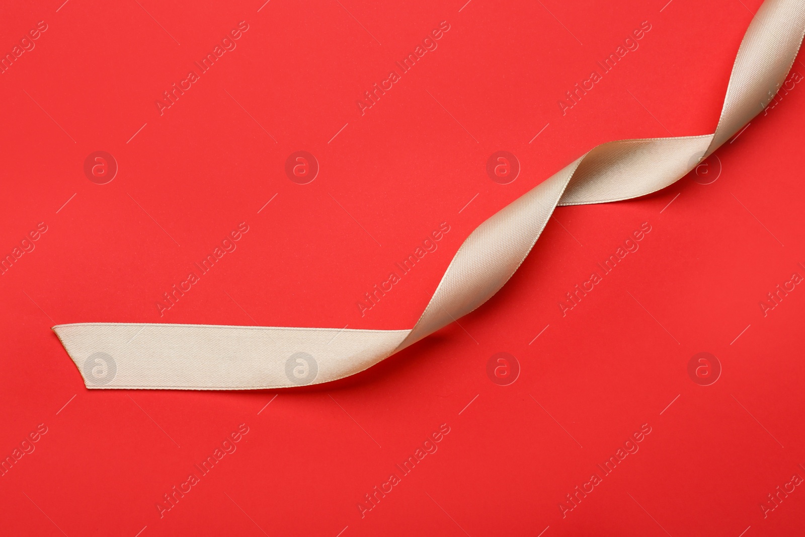 Photo of Beautiful ribbon on red background, top view