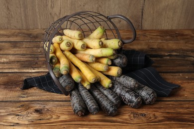 Photo of Many different raw carrots in metal basket on wooden table