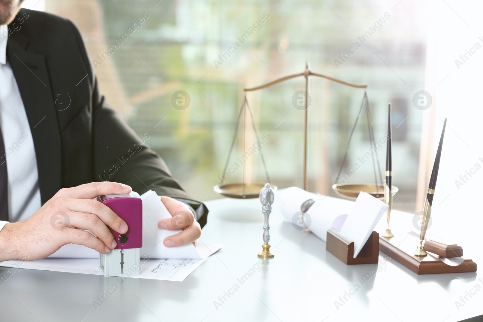 Photo of Male notary stamping document at table indoors, closeup