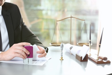 Photo of Male notary stamping document at table indoors, closeup