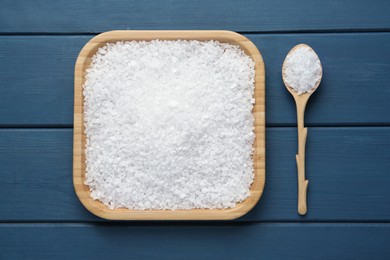 Plate and spoon with natural sea salt on blue wooden table, flat lay