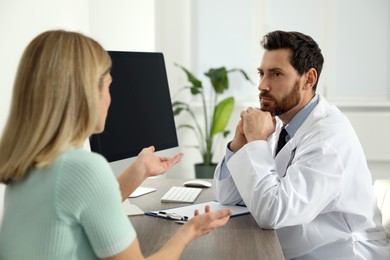 Photo of Doctor consulting patient at wooden table in clinic