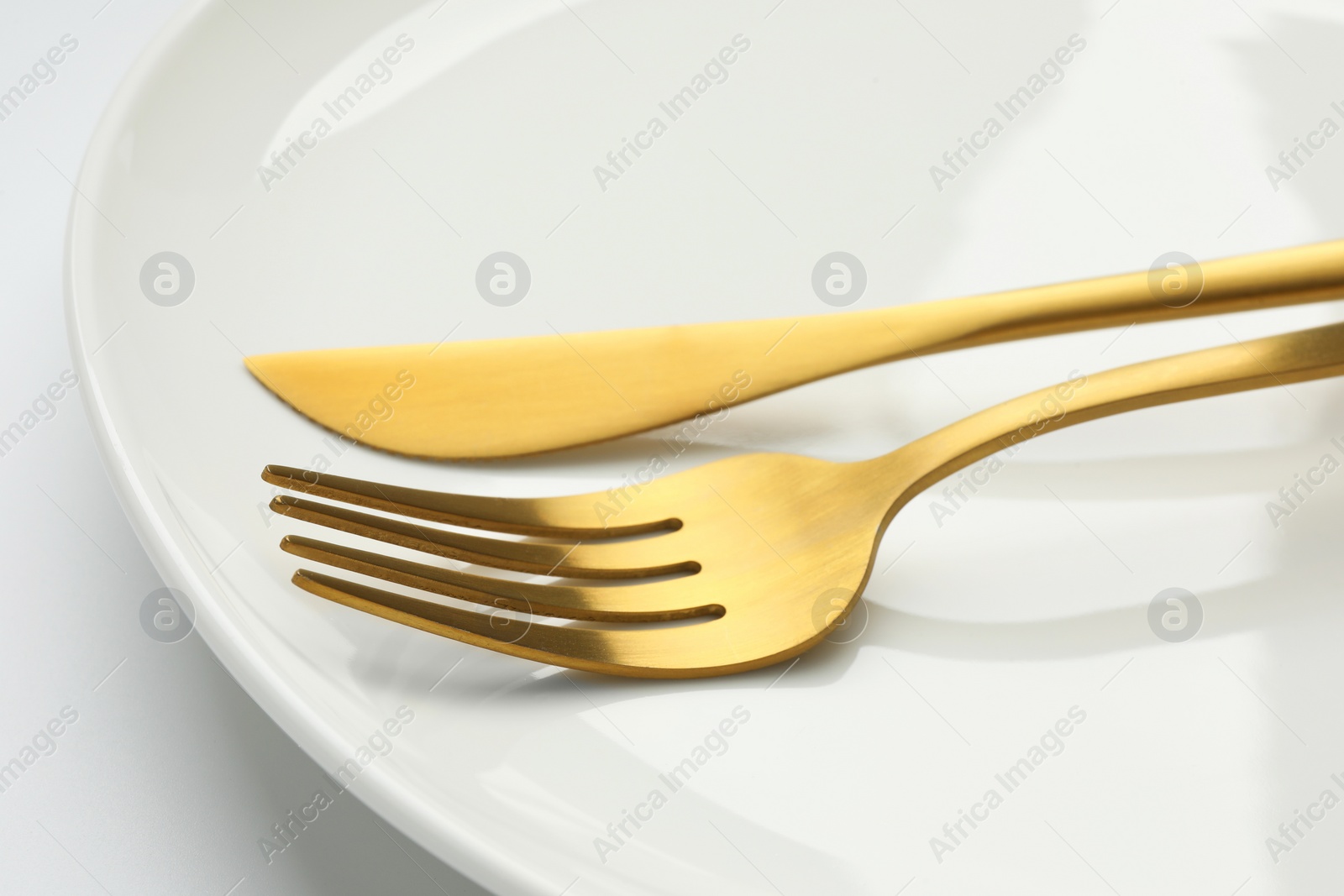 Photo of Clean plate, fork and knife on white background, closeup