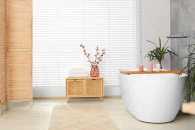 Stylish bathroom interior with beautiful tub, houseplants and decor elements