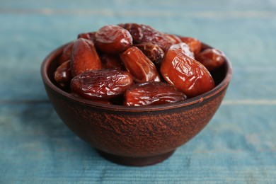 Photo of Sweet dried dates in bowl on light blue wooden table