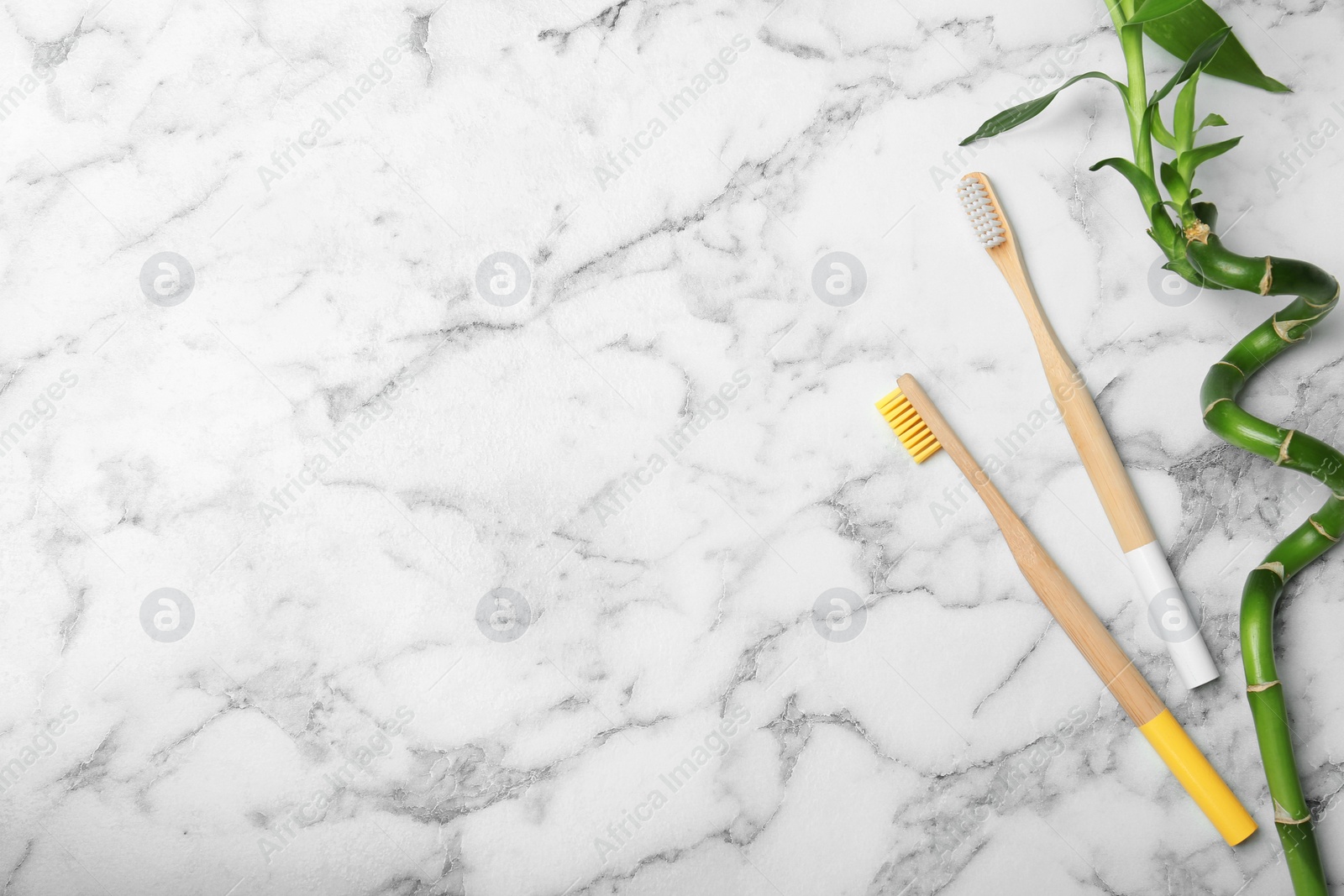 Photo of Flat lay composition with bamboo toothbrushes and space for text on marble background