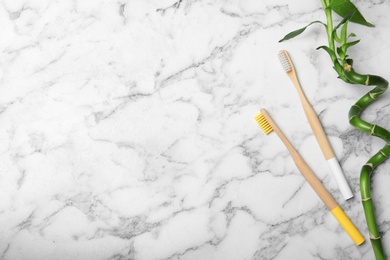 Flat lay composition with bamboo toothbrushes and space for text on marble background