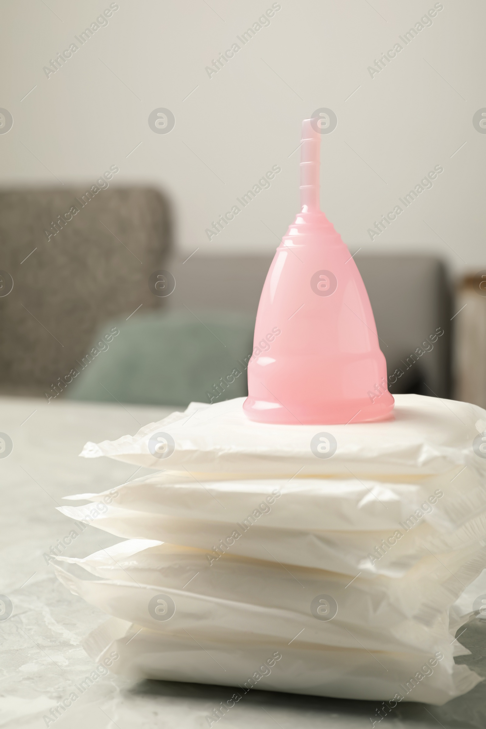 Photo of Menstrual cup and pads on grey table