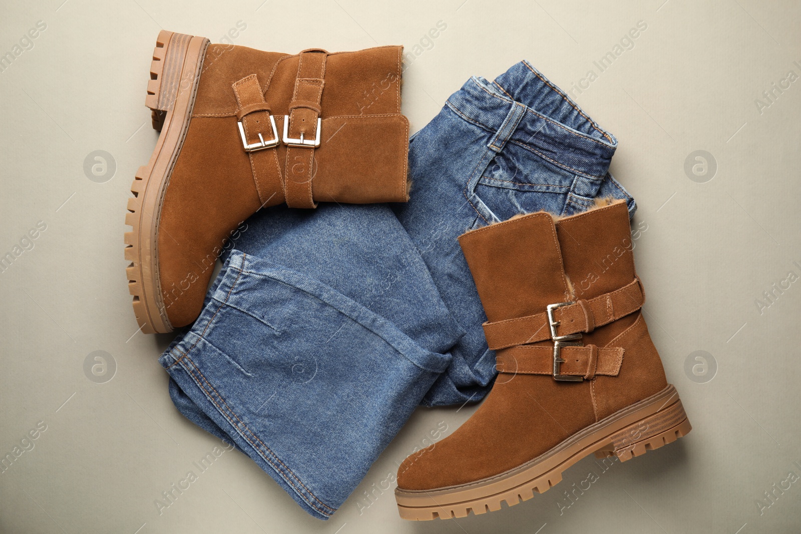 Photo of Stylish boots and jeans on grey background, flat lay