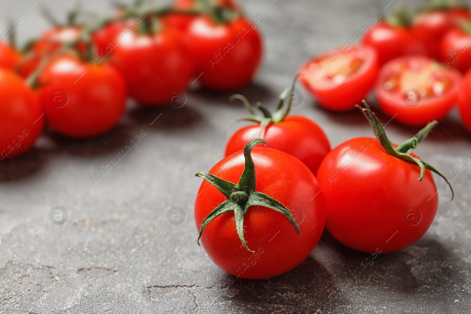 Photo of Fresh organic cherry tomatoes on stone background. Space for text