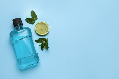 Photo of Mouthwash, mint and lime on light blue background, flat lay. Space for text