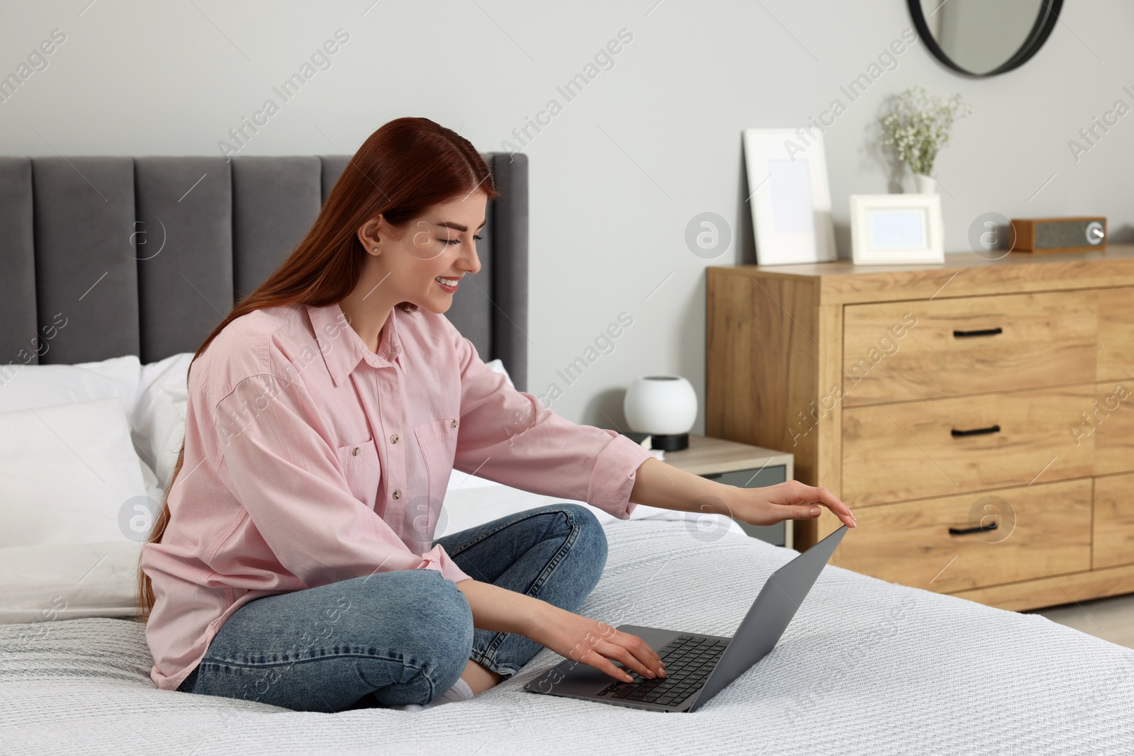 Photo of Happy woman with laptop on bed in bedroom