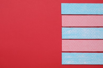 Photo of Sticks of tasty chewing gum on red background, flat lay. Space for text