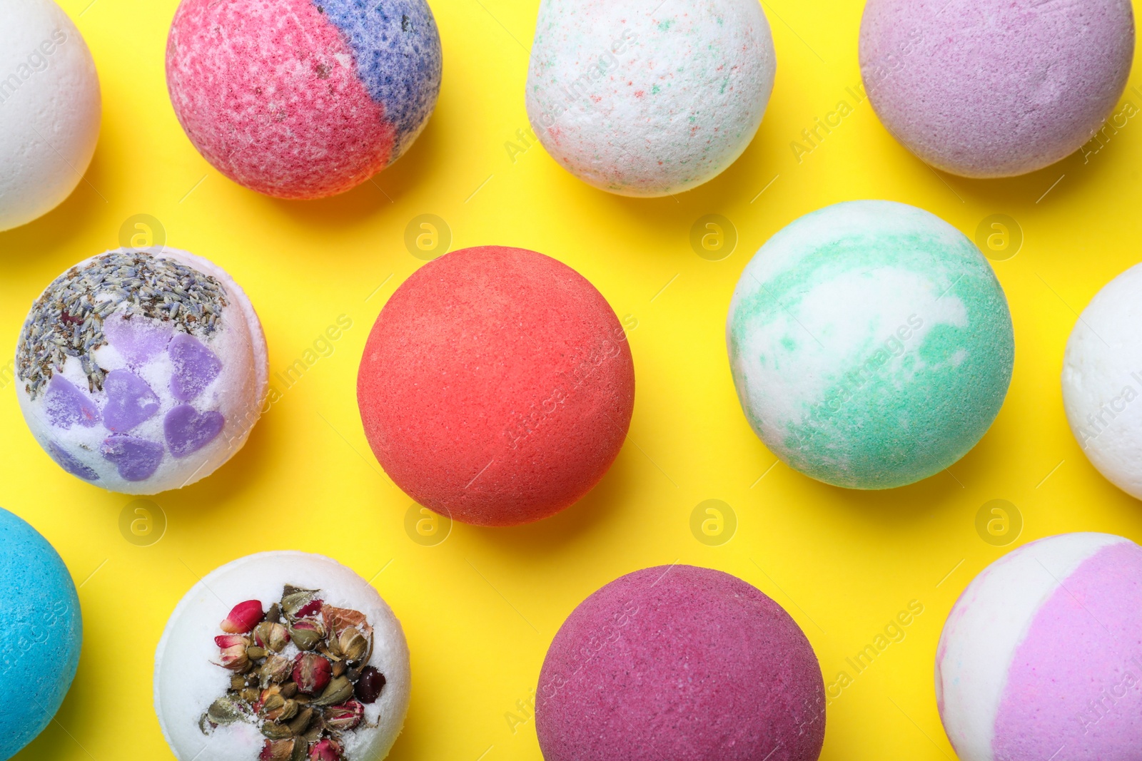 Photo of Colorful bath bombs on yellow background, flat lay