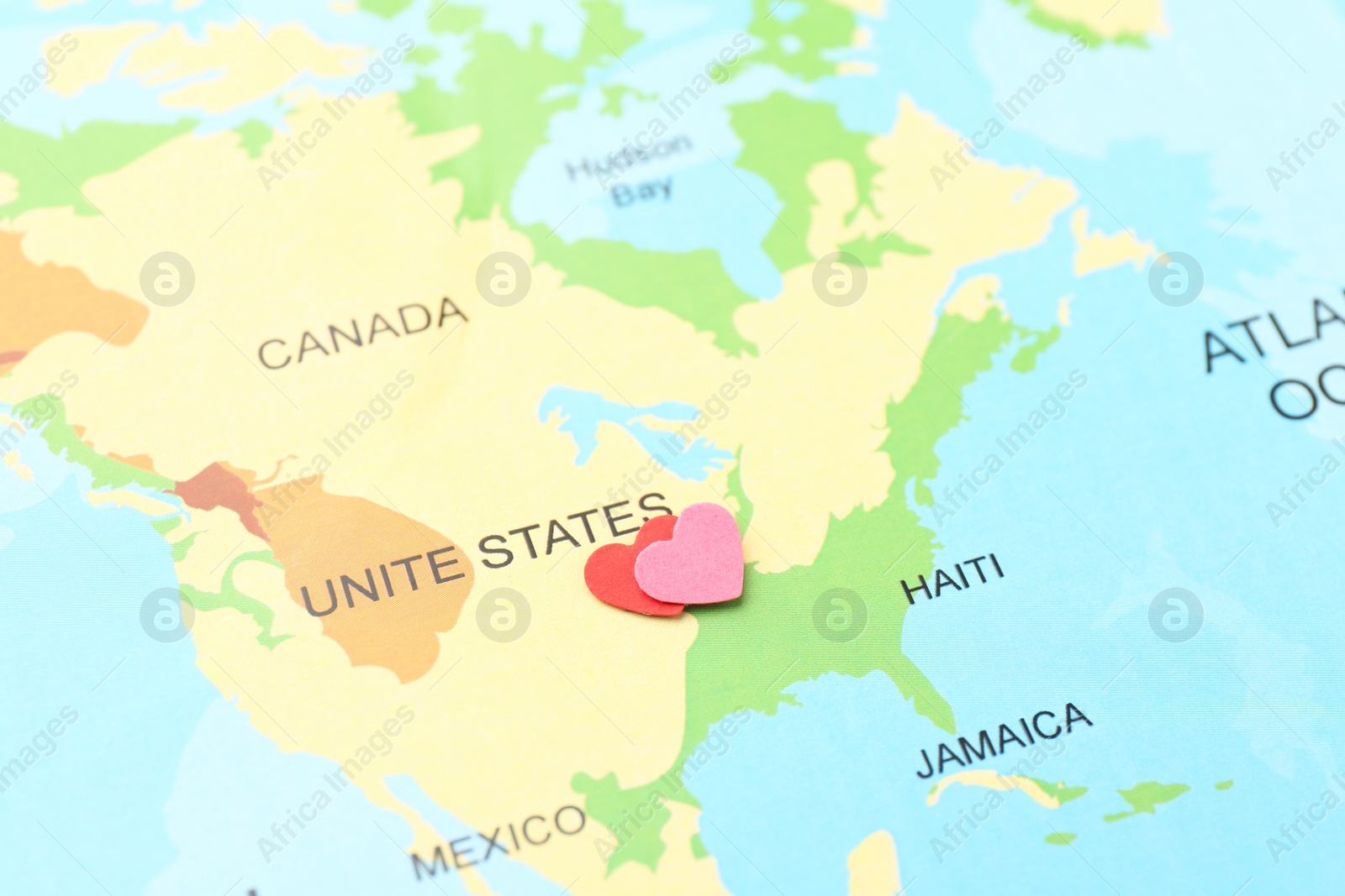 Photo of Honeymoon concept. Two red paper hearts on world map, closeup