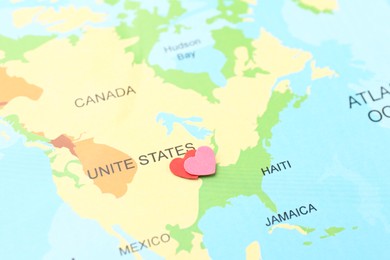 Honeymoon concept. Two red paper hearts on world map, closeup