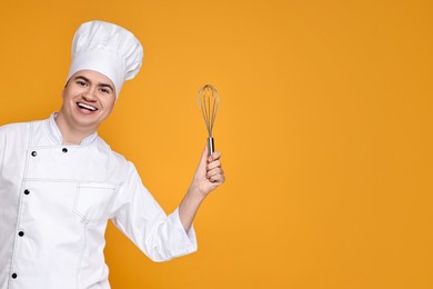 Photo of Portrait of happy confectioner in uniform holding whisk on orange background, space for text