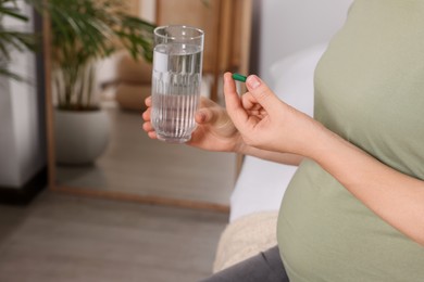 Photo of Pregnant woman taking pill at home, closeup