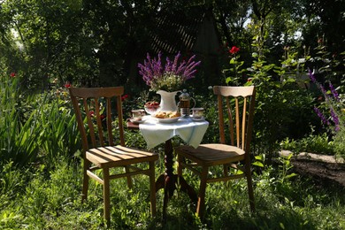 Photo of Beautiful bouquet of wildflowers on table served for tea drinking in garden