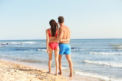 Happy young couple walking together on beach