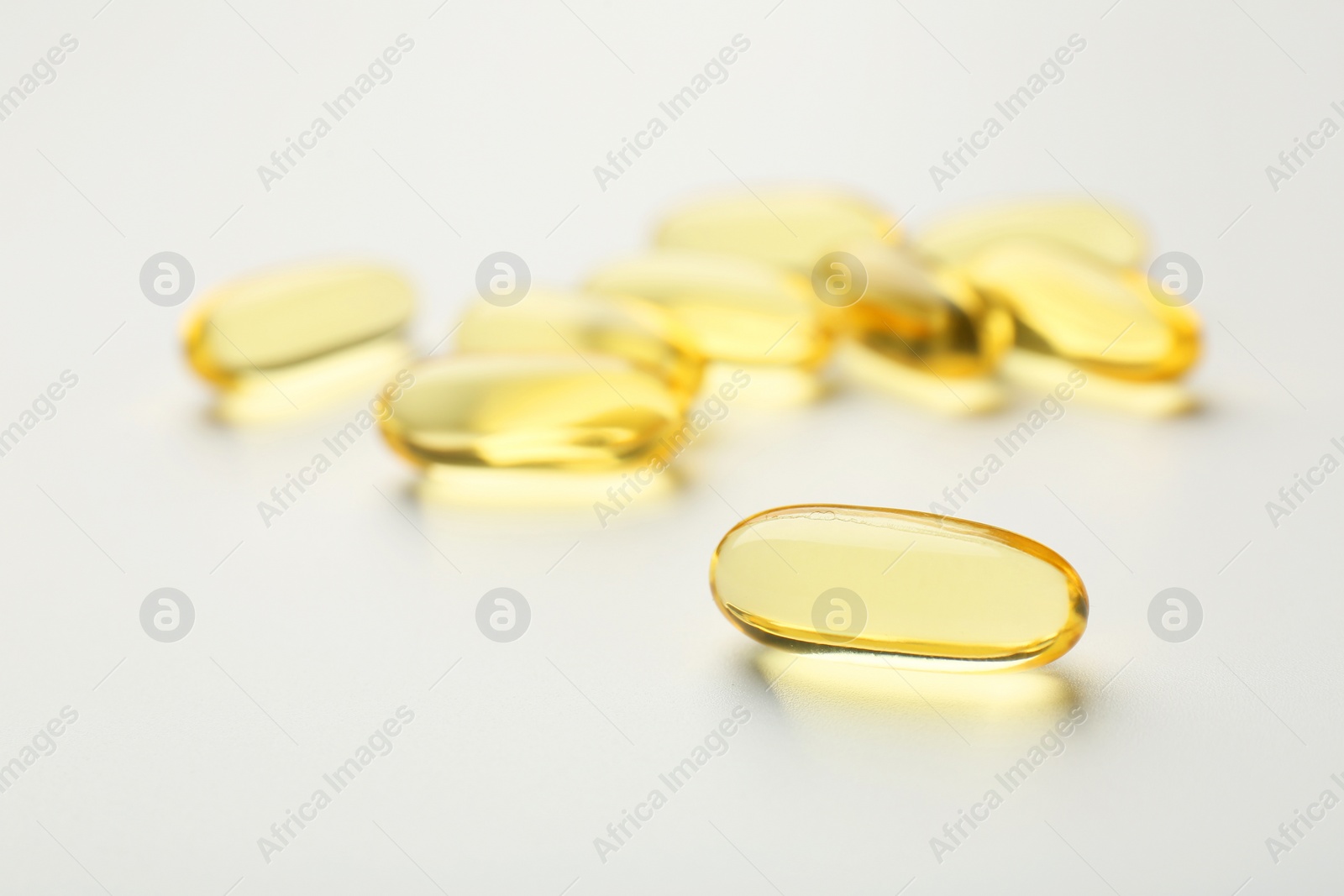 Photo of Yellow vitamin capsules on white background, closeup
