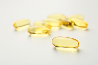 Yellow vitamin capsules on white background, closeup
