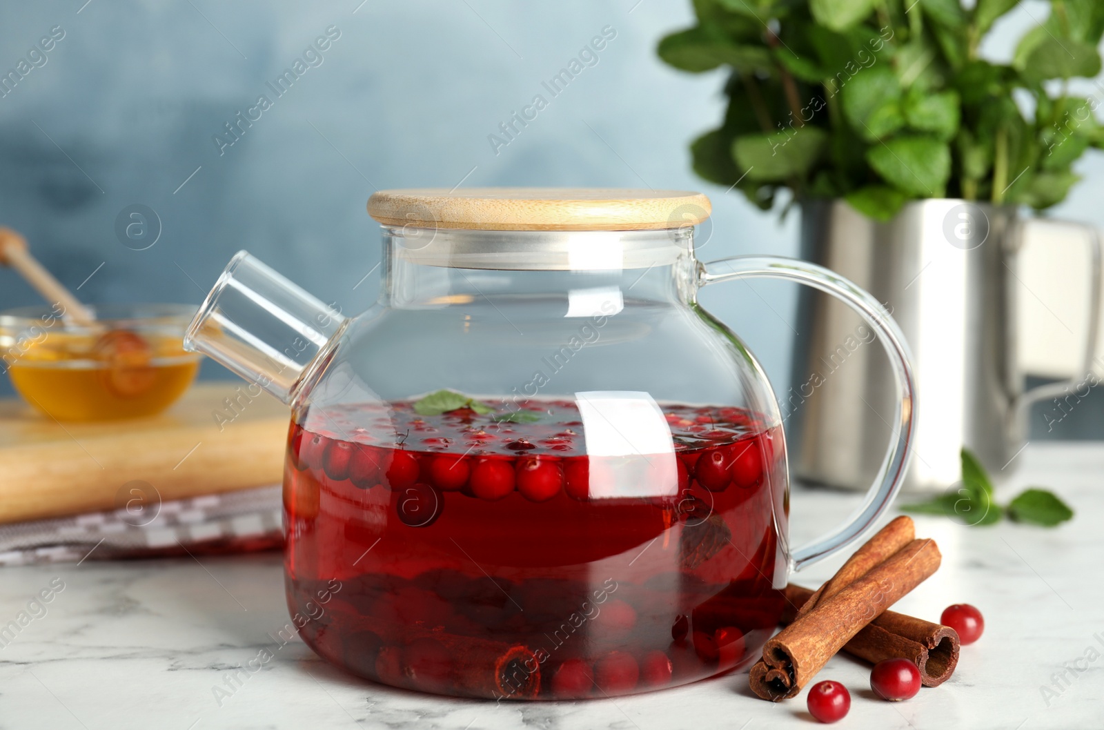 Photo of Tasty hot cranberry tea with mint and cinnamon on white marble table