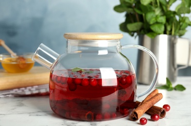 Photo of Tasty hot cranberry tea with mint and cinnamon on white marble table