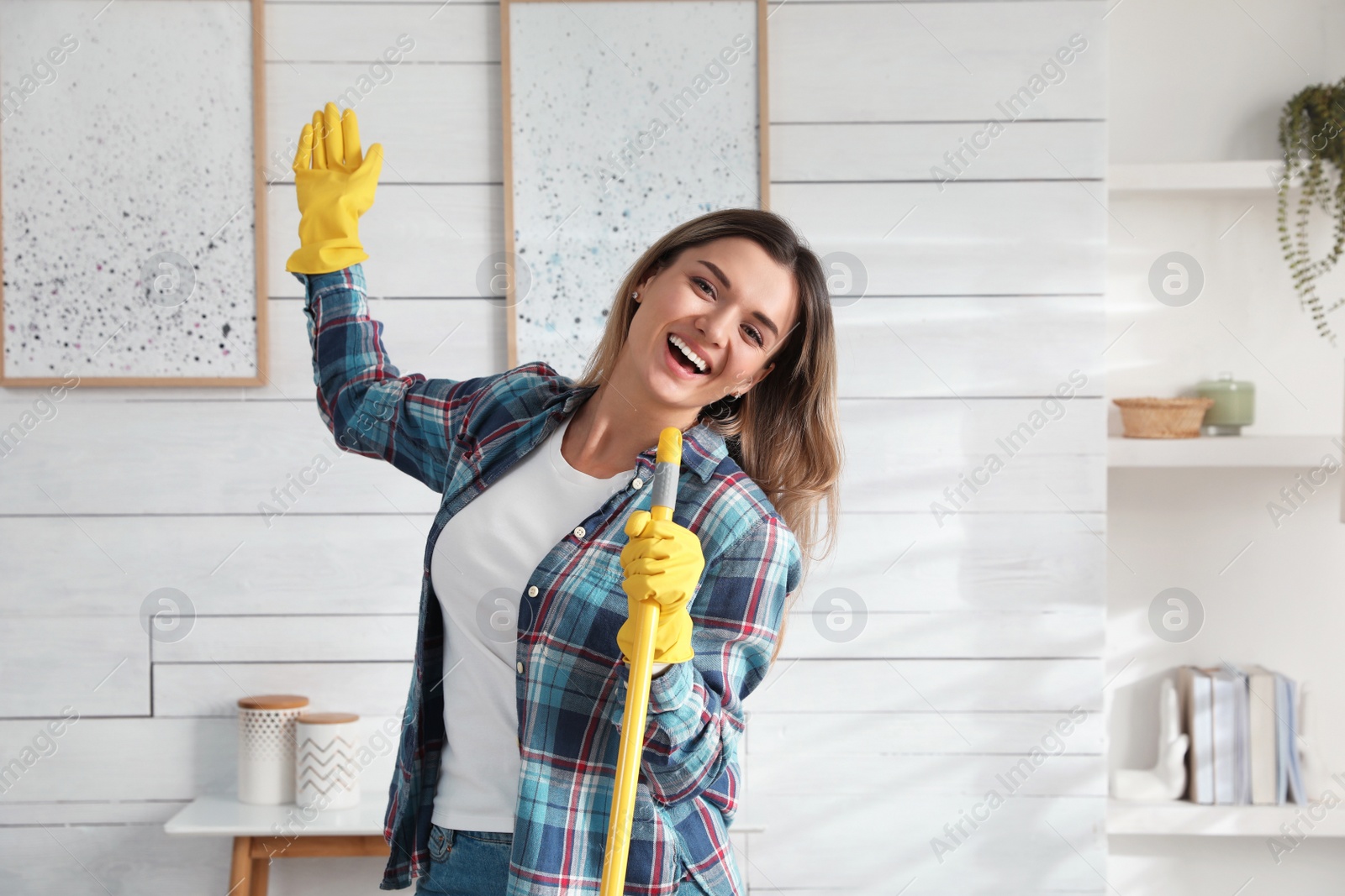 Photo of Woman with mop singing while cleaning at home