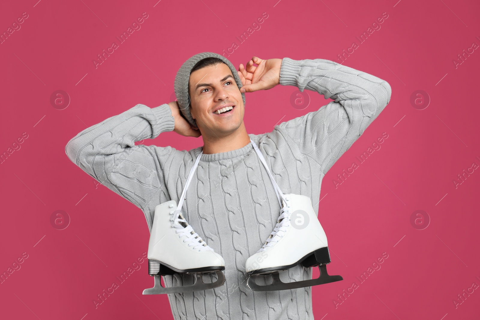 Photo of Happy man with ice skates on pink background