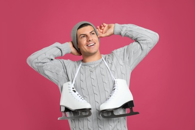 Happy man with ice skates on pink background