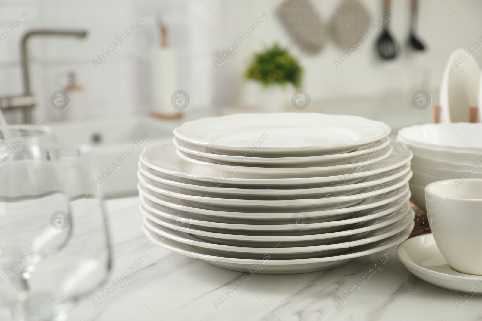 Photo of Clean plates and cup on white marble countertop in kitchen