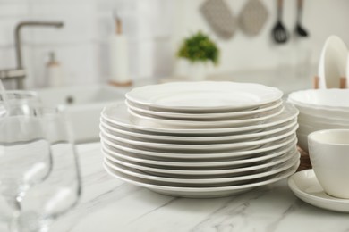 Clean plates and cup on white marble countertop in kitchen