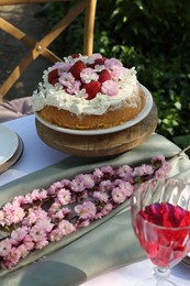 Beautiful spring flowers and delicious cake on table in garden