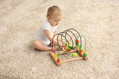 Photo of Children toys. Cute little boy playing with bead maze on rug at home