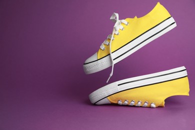 Photo of Pair of yellow classic old school sneakers on purple background, space for text