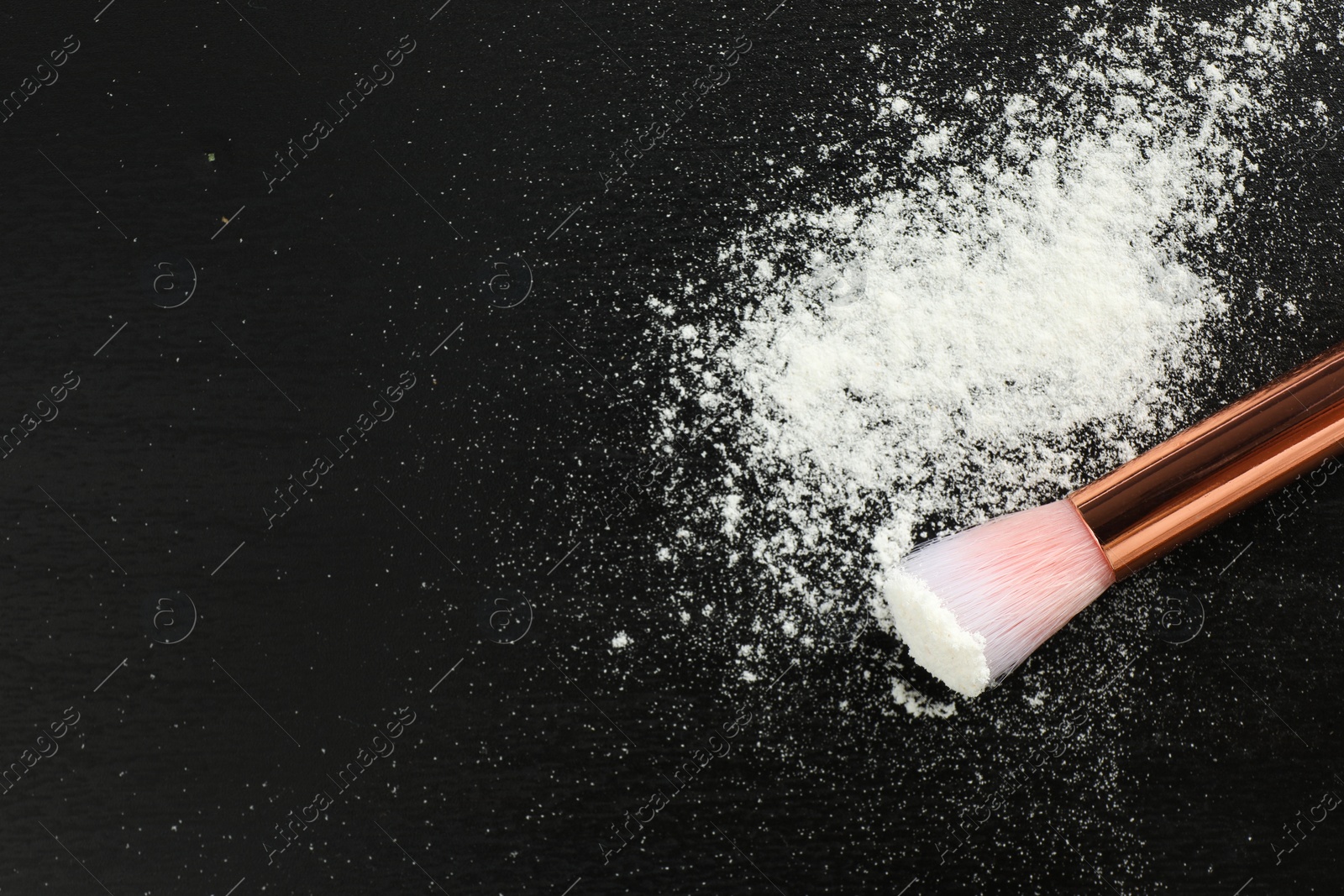 Photo of Rice loose face powder and makeup brush on black background, above view. Space for text