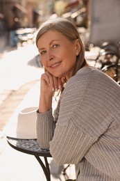 Photo of Beautiful senior woman sitting in outdoor cafe