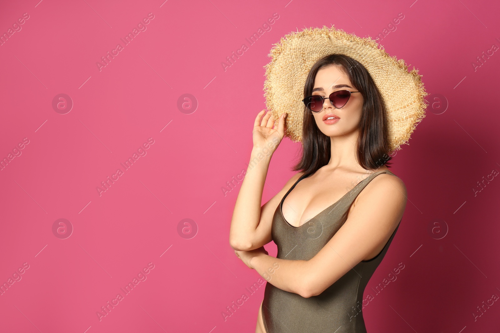 Photo of Beautiful young woman wearing swimsuit, hat and sunglasses on pink background. Space for text