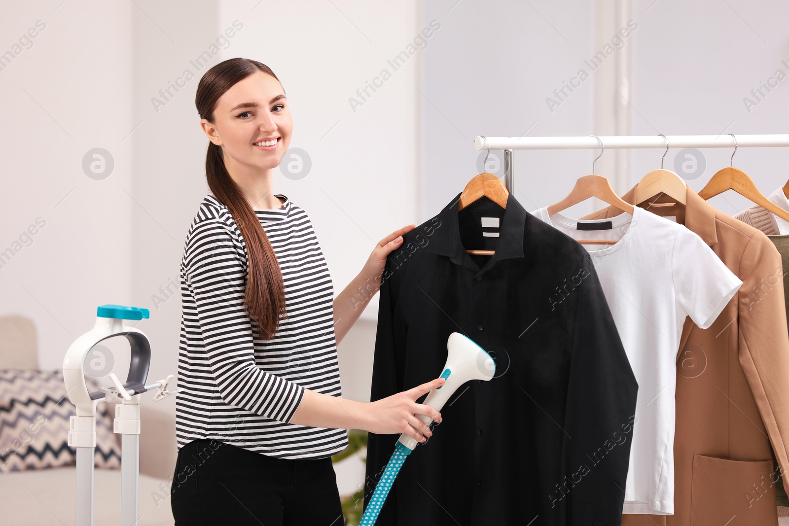 Photo of Woman steaming black shirt on hanger at home