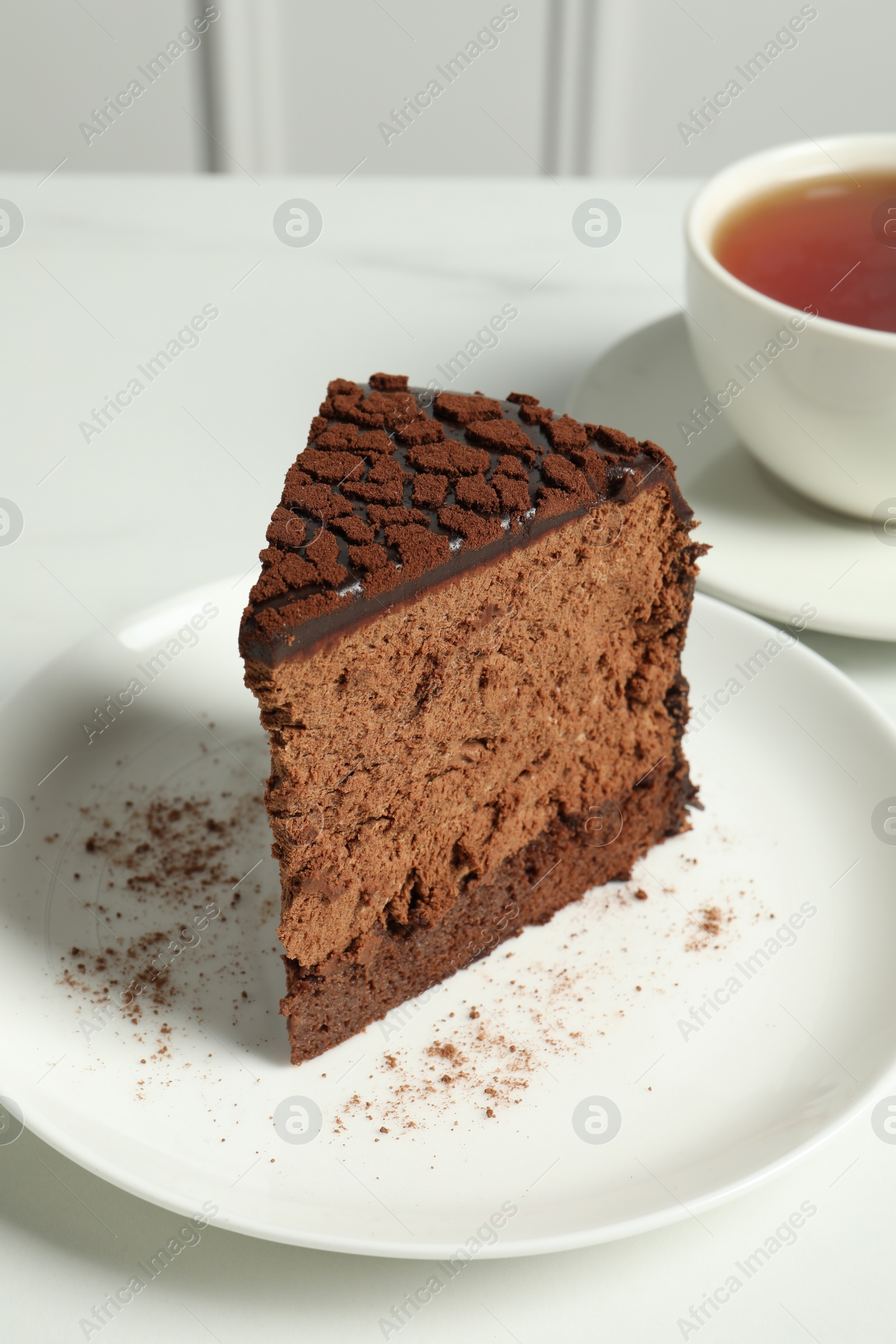 Photo of Piece of delicious chocolate truffle cake on white table, closeup