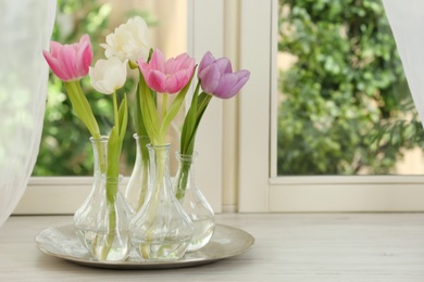 Photo of Beautiful fresh tulips on window sill indoors. Spring flowers
